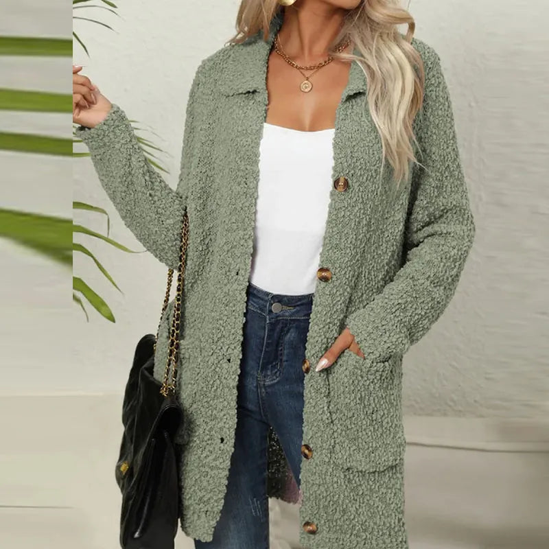 Frau in Armeegrünem Strickmantel, weißem Top, Jeans; modischer Herbst-Look.