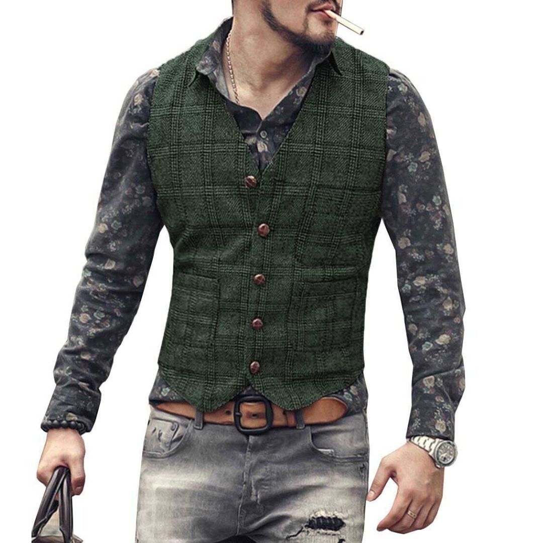 Mann in grüner Weste, gemustertem Hemd, zerrissener Jeans, mit Uhr und Tasche, rauchend.