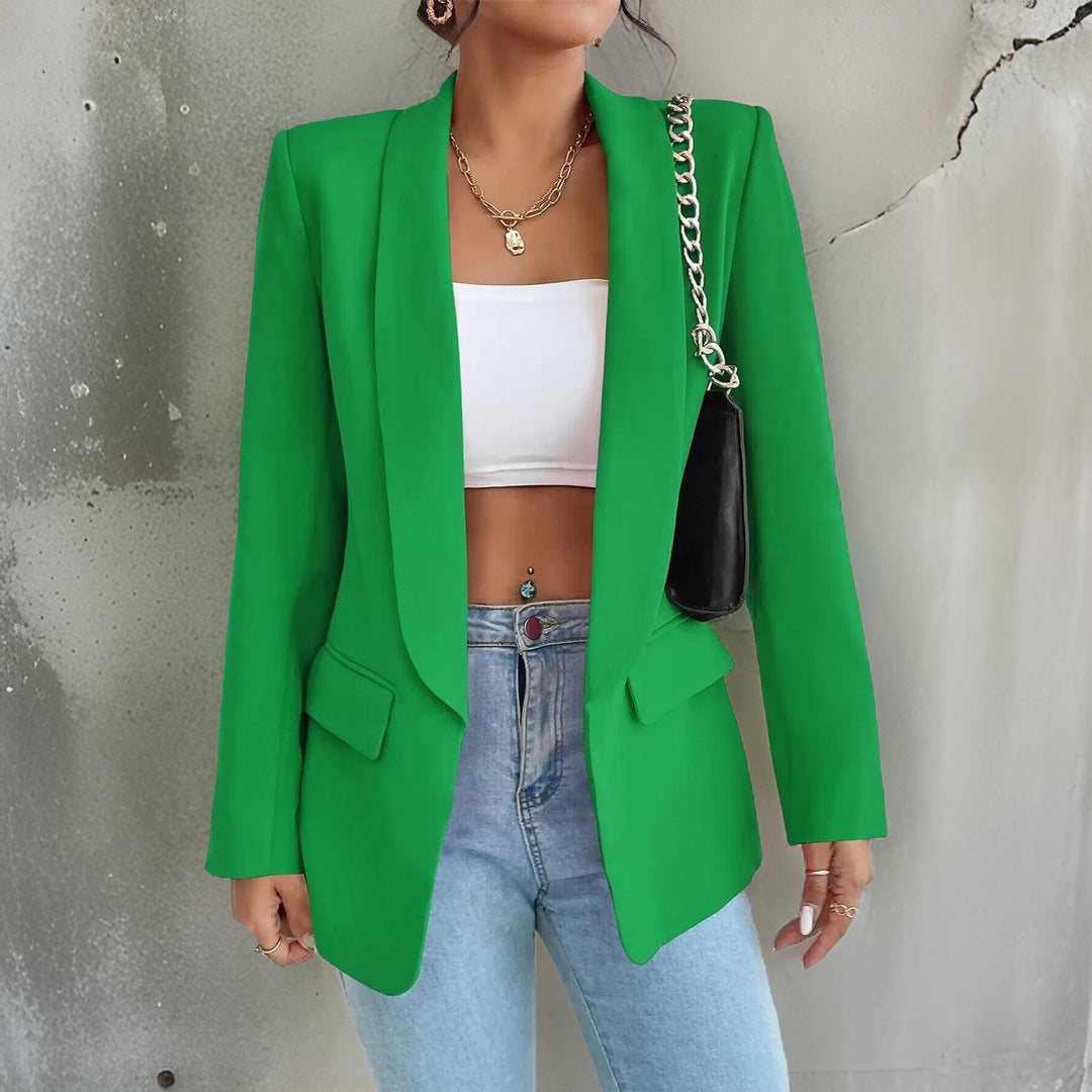 Frau in grünem Blazer, weißem Top und blauer Jeans, modisch, urbaner Stil.