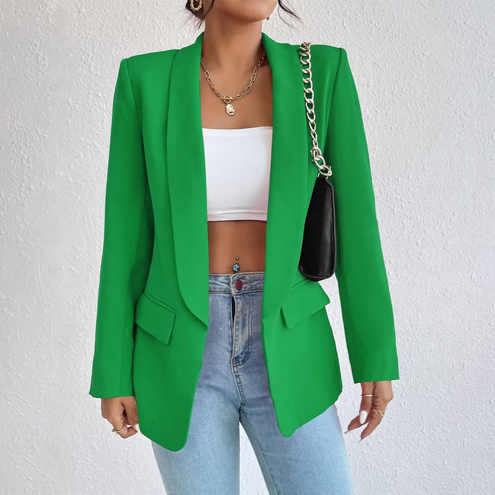 Frau in grünem Blazer, weißem Top, blauer Jeans, goldene Kette, schwarze Tasche.
