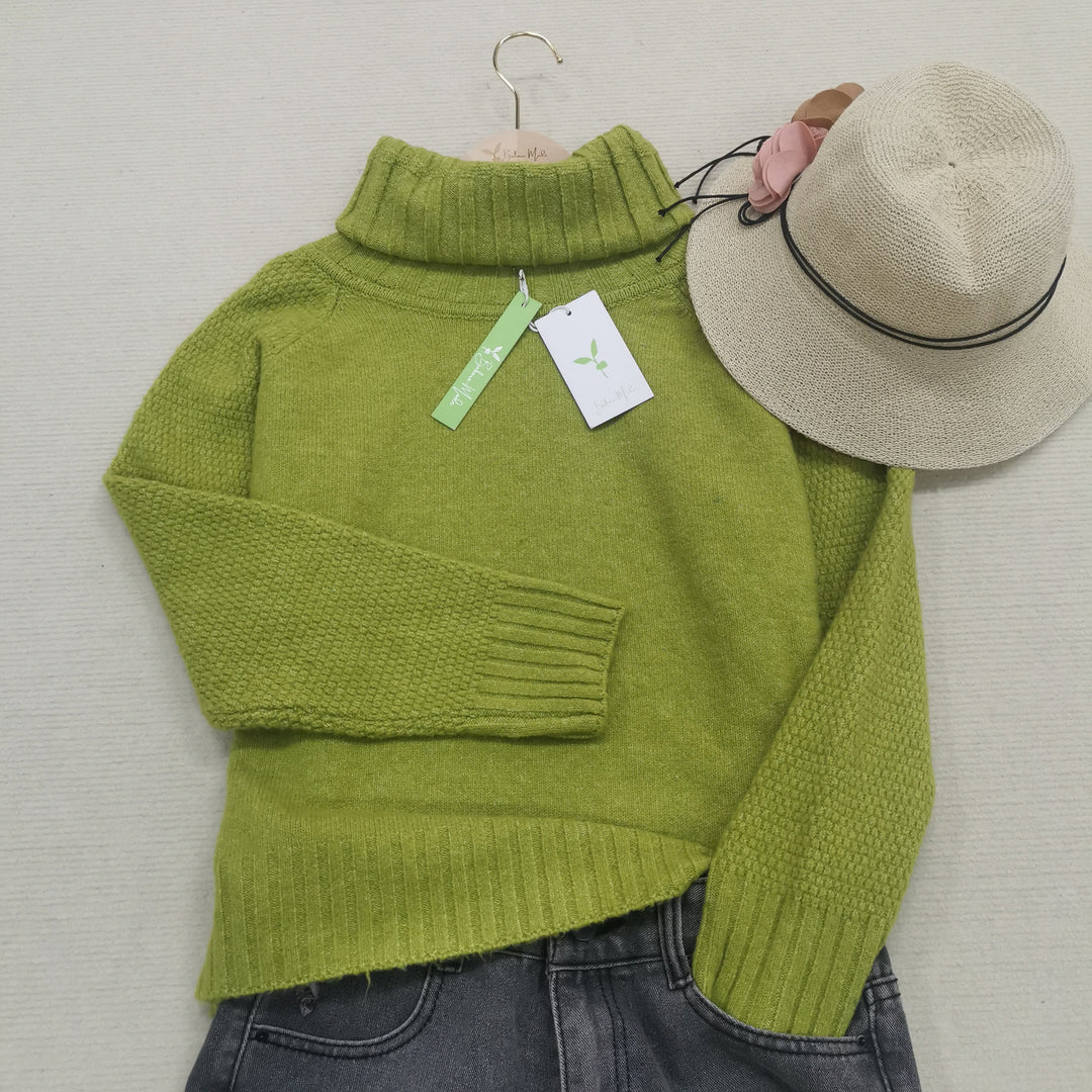 Grüner Rollkragenpullover aus Wolle mit Etikett, beige Hut, graue Jeans, flach gelegt.