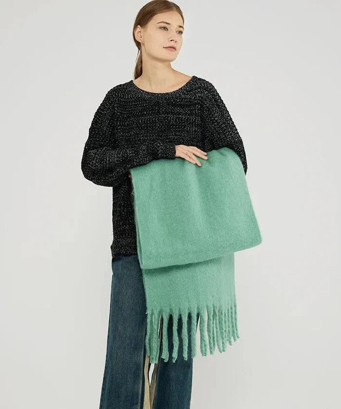 Frau mit schwarzem Pullover und grüner Wollschal mit Fransen, modisch, gemütlich, Herbstbekleidung.