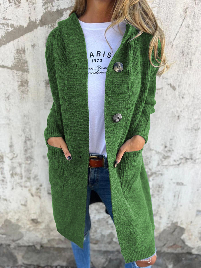 Frau in grünem Strickmantel mit Kapuze, weiße T-Shirt, blaue Jeans, lässiger Herbstlook.