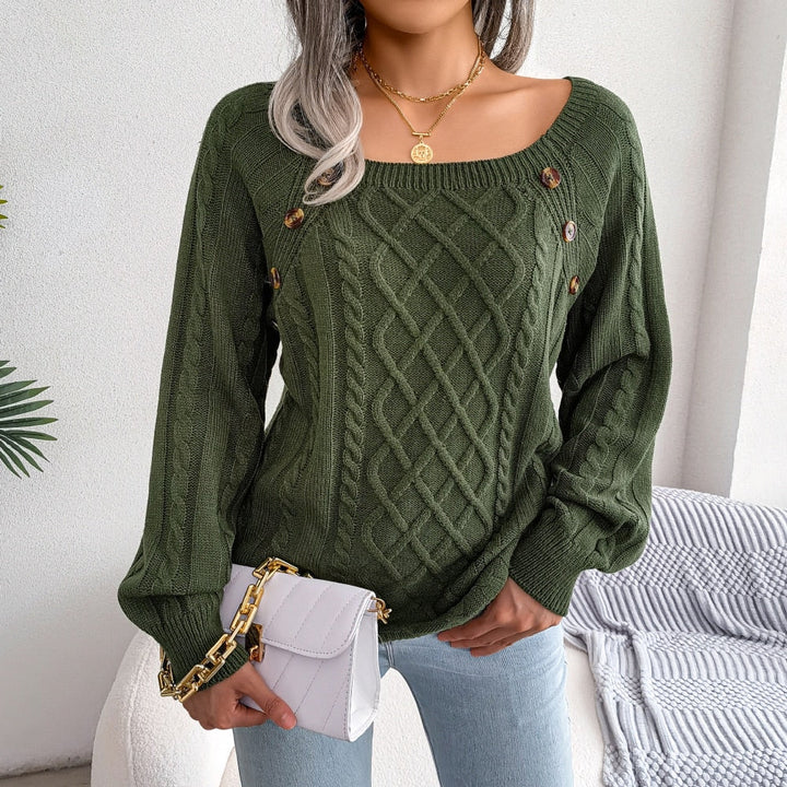 Frau trägt grünen Strickpullover mit Zopfmuster, goldene Knöpfe, weiße Umhängetasche.