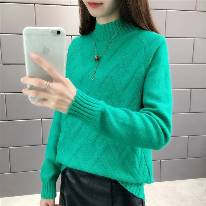 Frau in grünem Strickpullover mit hohem Kragen, Smartphone in der Hand, moderne Mode.