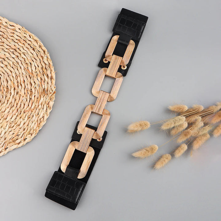 Schwarzer Gürtel mit Holzketten-Elementen, modisches Accessoire, Damenmode, auf grauem Hintergrund.