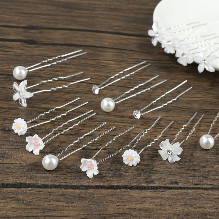 Haarpins mit weißen Blumen und Perlen auf Holztisch, Hochzeit Haarschmuck, elegant und stilvoll.