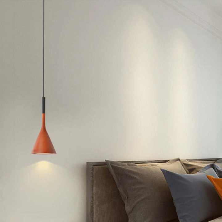 Moderne rote Pendelleuchte über einem Bett mit grauen Kissen, minimalistische Schlafzimmerbeleuchtung.