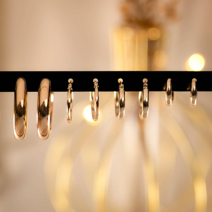 Goldene Creolen Ohrringe auf schwarzem Ständer, verschiedene Größen, eleganter Schmuck.
