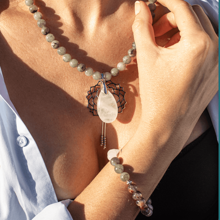 Frau mit Labradorit-Halskette und Armband, weißer Anhänger, eleganter Schmuck, Nahaufnahme.