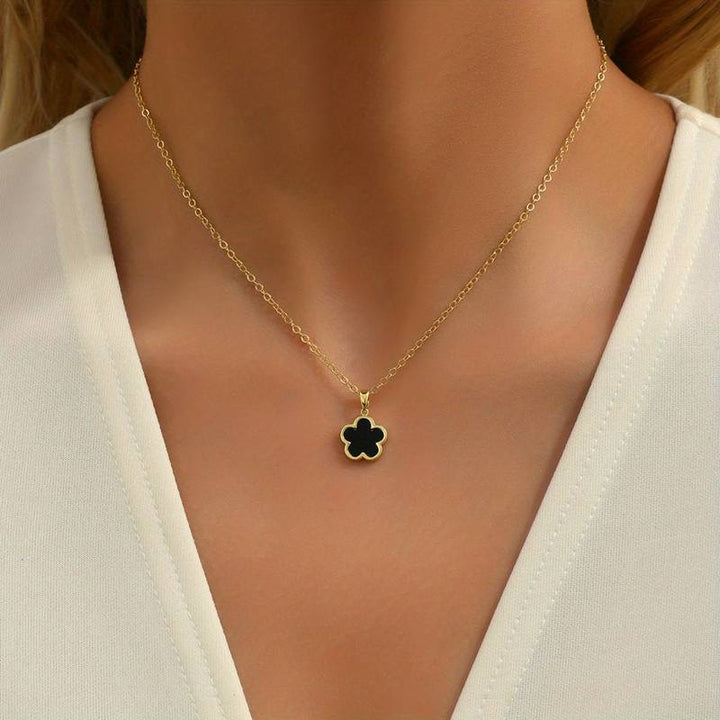 Goldene Halskette mit schwarzem Blumenanhänger, eleganter Schmuck für Damen, modisches Accessoire.