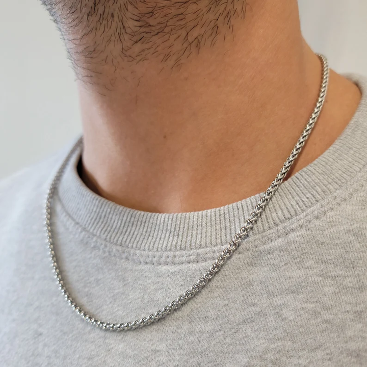 Silberne Halskette, geflochtenes Design, getragen von Mann, modisches Schmuckstück.