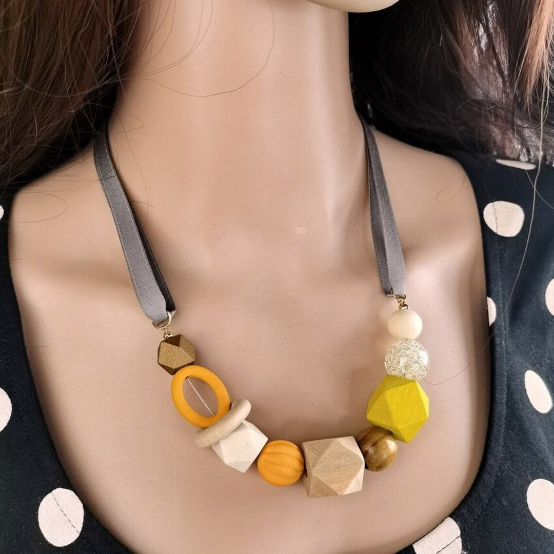 Bunte Halskette aus Holzperlen, geometrische Formen, gelb und grau, modisches Accessoire.