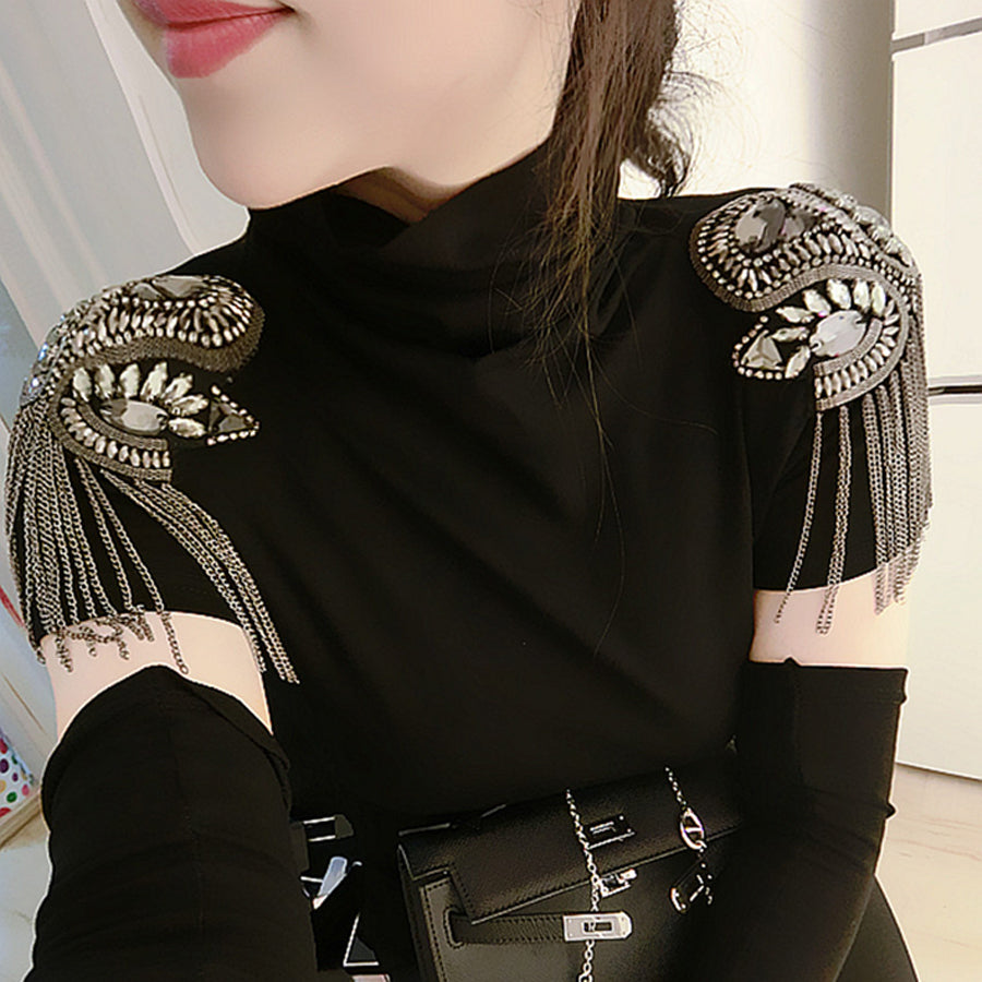 Frau trägt schwarzes Kleid mit handgemachten Strass-Epauletten und Kettendetails.