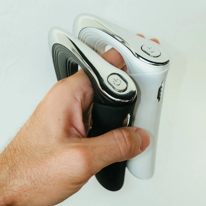 Hand hält zwei elektrische Rasierer, schwarz und weiß, ergonomisches Design, Nahaufnahme.
