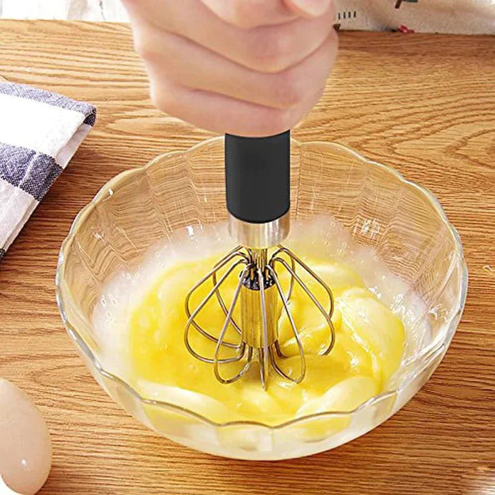 Handmixer aus Edelstahl in Glasschüssel, ideal zum Eier schlagen, Küchenutensil, Holzoberfläche.