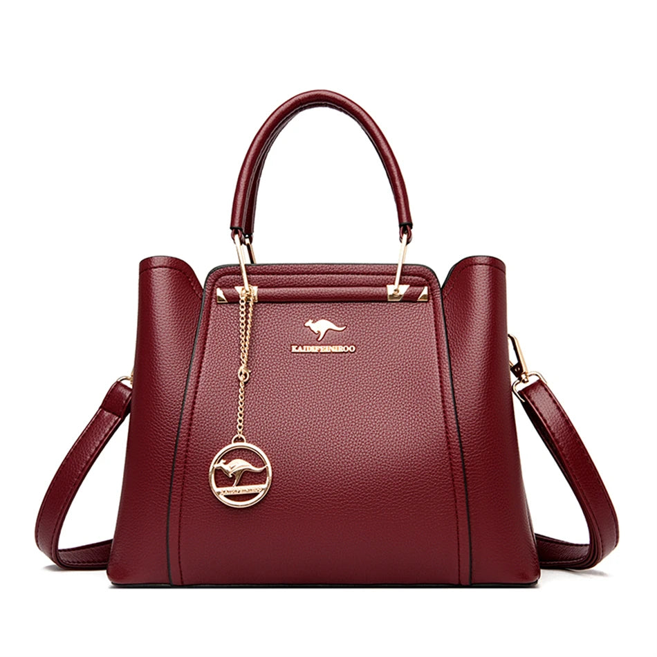 Bordeauxrote Damenhandtasche aus Leder mit goldenen Details und Känguru-Logo, elegant, modisch.