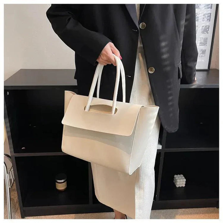 Frau mit weißer Ledertasche, elegantes Design, Büro-Outfit, schwarze Jacke, moderne Mode.