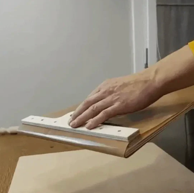 Hand glättet Holzfurnier mit Spachtel, DIY-Möbelbau, Holzverarbeitung, Heimwerkerprojekt.