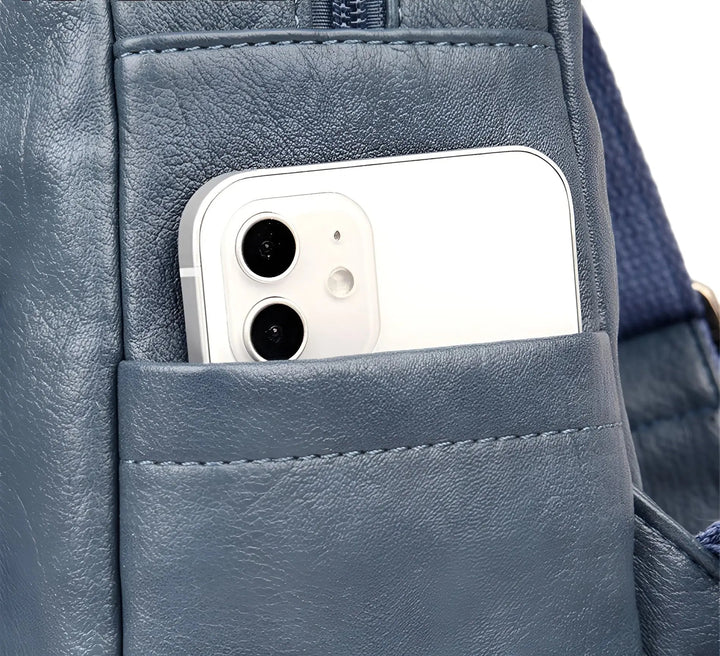 Blaues Lederrucksackfach mit weißem Smartphone, modernes Design, stilvolle Aufbewahrung.