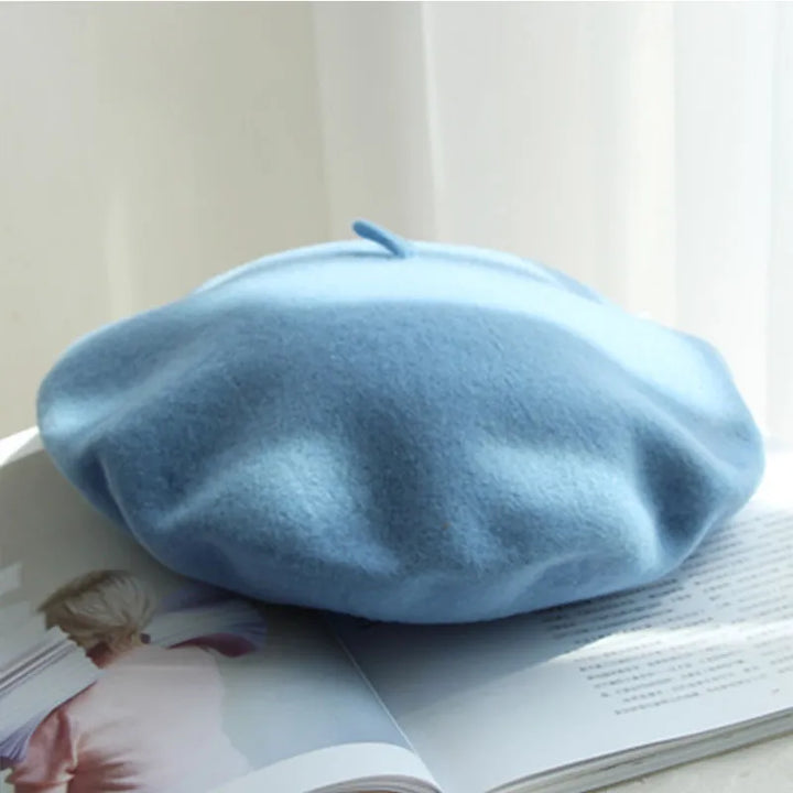 Himmelblaues Woll-Barett auf offenem Buch, stilvolles Accessoire für Damenmode.