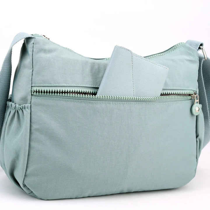 Hellblaue Umhängetasche aus Stoff mit Reißverschluss und Außentasche, ideal für Damen.