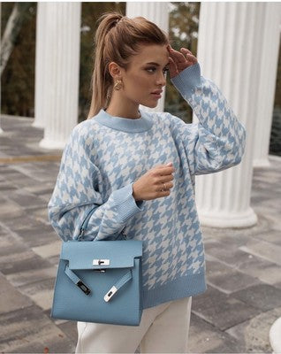 Frau mit blau-weißem Hahnentritt-Pullover und blauer Handtasche vor Säulen.