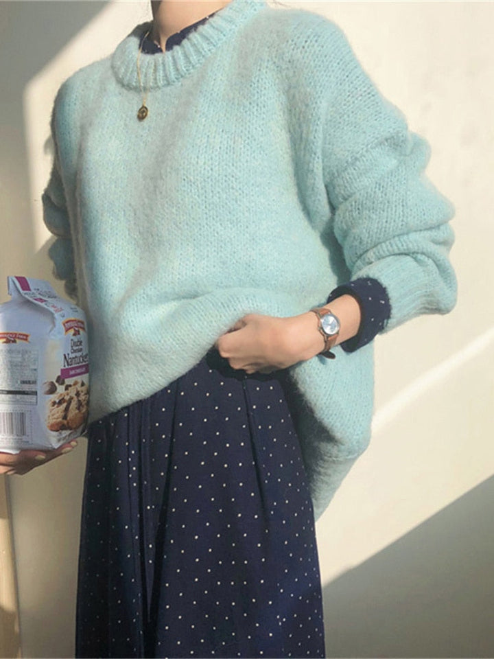 Frau in hellblauem Strickpullover, dunkelblaues gepunktetes Kleid, hält Keksmischung.