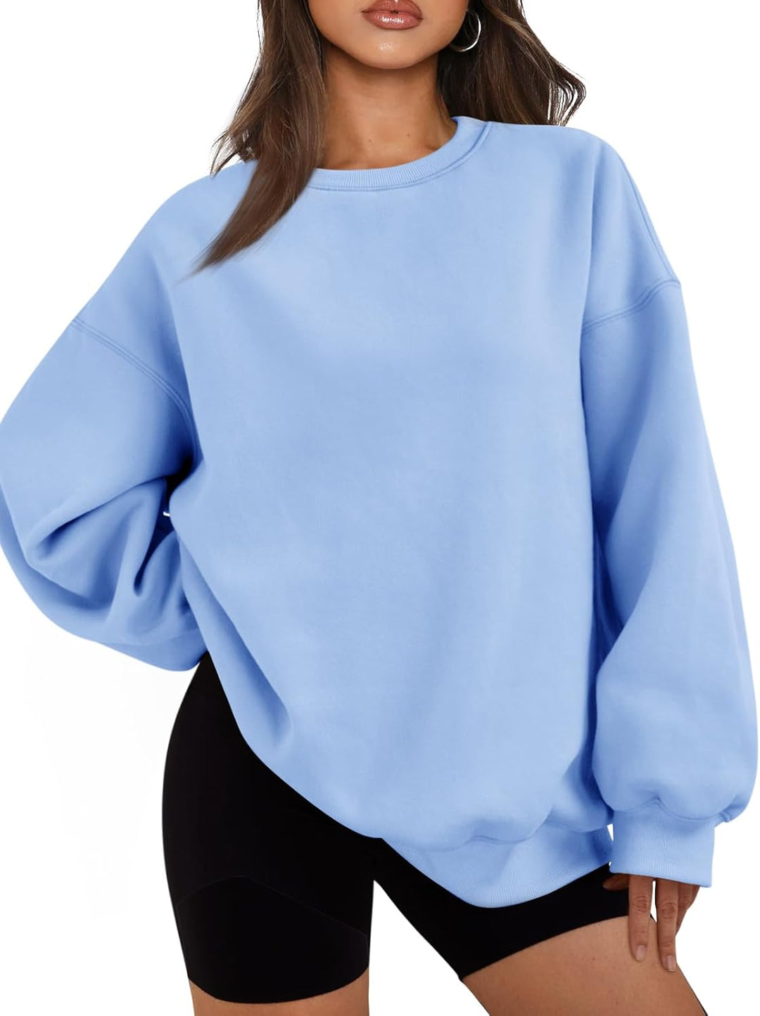 Frau in hellblauem Oversize-Sweatshirt und schwarzen Shorts, lässige Mode, Streetwear-Trend.