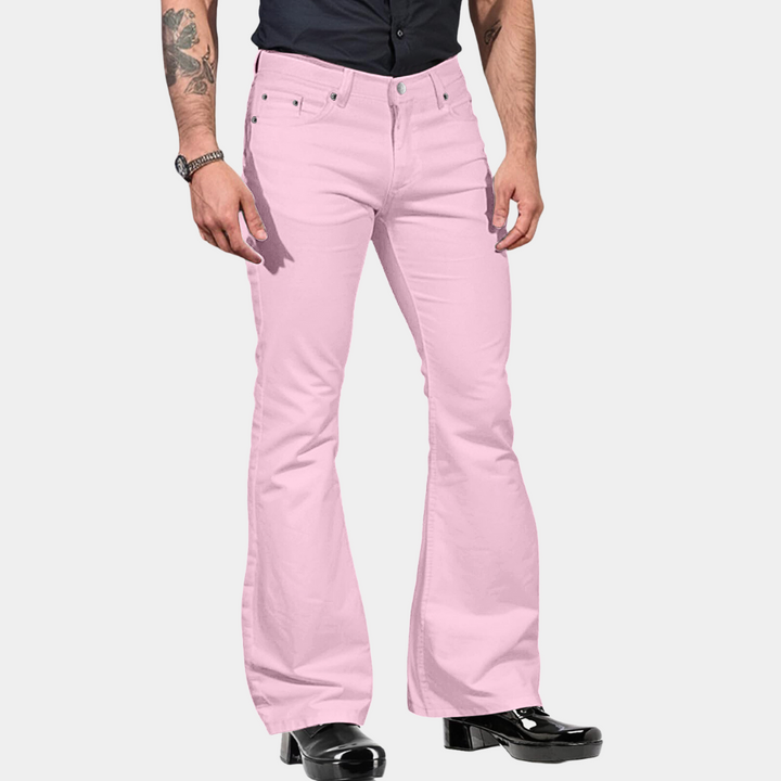 Mann in rosa Schlaghose, schwarze Stiefel, schwarzes Hemd, modische Herrenbekleidung.