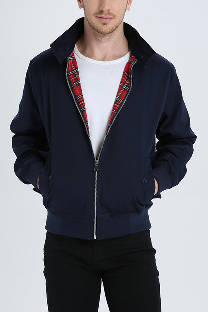 Mann in dunkelblauer Harrington-Jacke mit rotem Karofutter, weißem T-Shirt und schwarzer Hose.