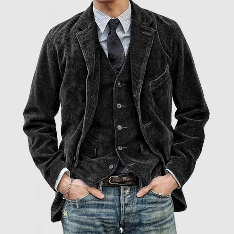 Mann in schwarzem Cord-Sakko mit Weste, gestreiftem Hemd und Jeans, modischer Herrenstil.