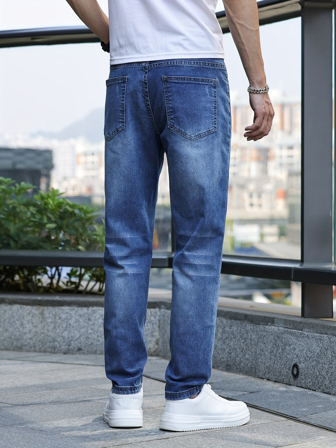 Mann in blauer Jeans und weißen Sneakers, Rückansicht, urbaner Hintergrund.