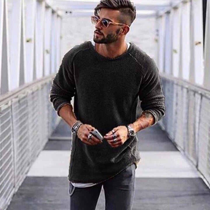 Mann mit schwarzem Pullover und Sonnenbrille auf Brücke, modischer Herrenstil, urbaner Look.