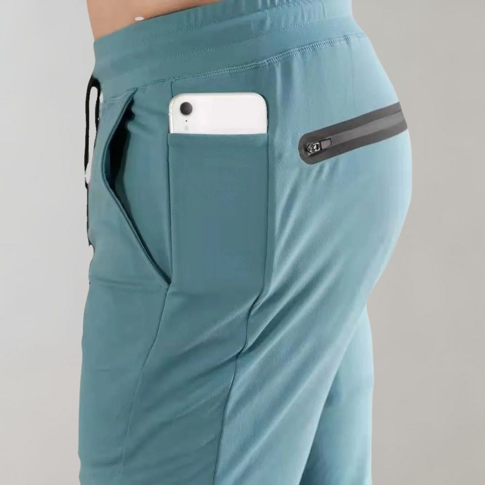 Grüne Sportshorts mit Reißverschlusstasche, Smartphone in der Tasche, seitliche Ansicht.