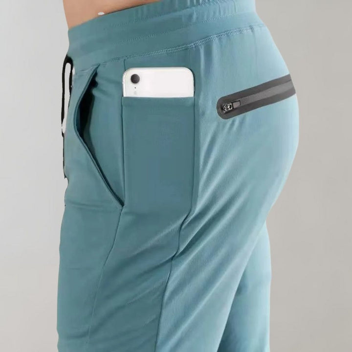 Grüne Sportshorts mit Reißverschlusstasche, Smartphone in der Tasche, seitliche Ansicht.