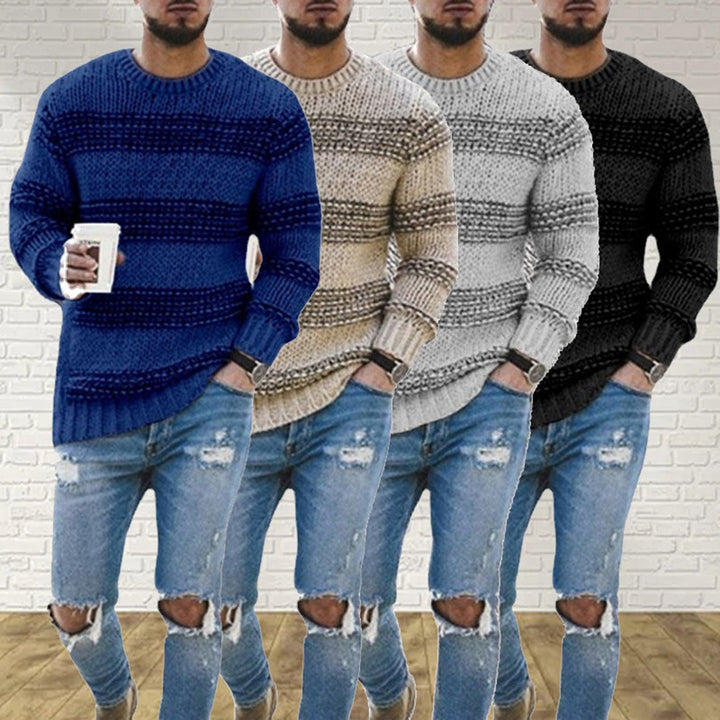 Vier Herrenpullover in Blau, Beige, Grau und Schwarz, grob gestrickt, vor weißer Ziegelwand.