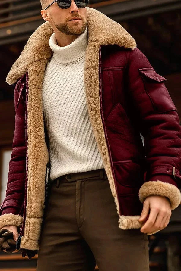 Mann in burgunderroter Lammfelljacke, weißem Rollkragenpullover, brauner Hose, Sonnenbrille.