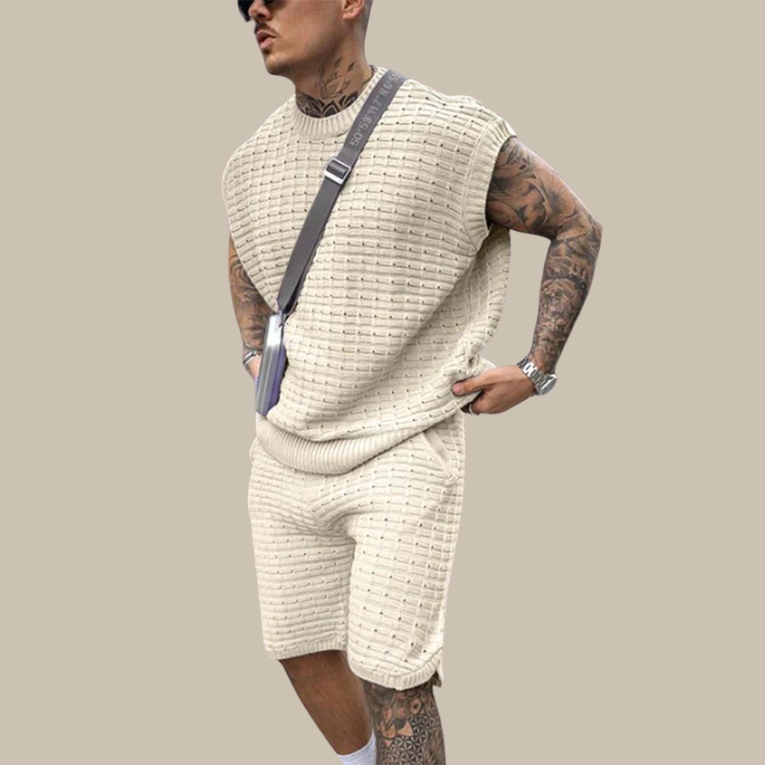 Mann in cremefarbenem Strick-Set mit ärmellosem Oberteil und Shorts, modisch, lässig.