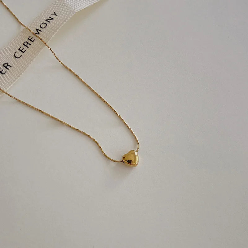 Goldene Herz-Halskette auf weißem Hintergrund, elegantes Schmuckdesign, minimalistisch.