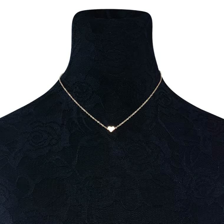 Goldene Herz-Halskette auf schwarzem Schmuckständer, elegantes Design, Damen-Schmuck.