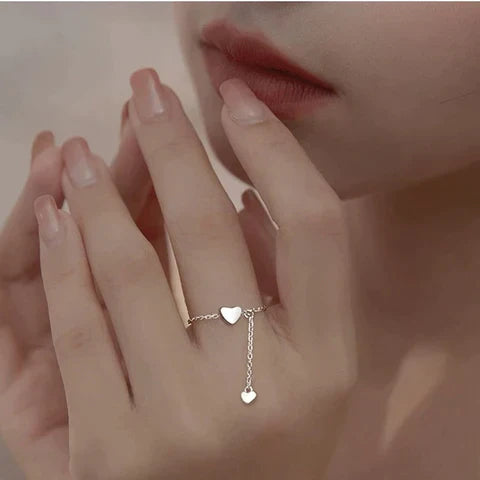 Frau mit silbernem Herzring, zarte Kette, eleganter Schmuck, romantisches Design.