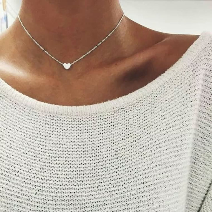 Silberne Herz-Halskette auf weißem Strickpullover, eleganter Schmuck für Damen.