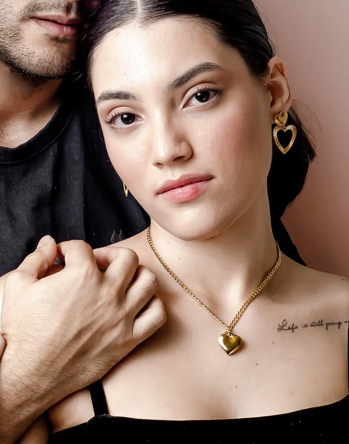 Frau mit goldenen Herz-Ohrringen und Halskette, eleganter Schmuck, romantisches Design.