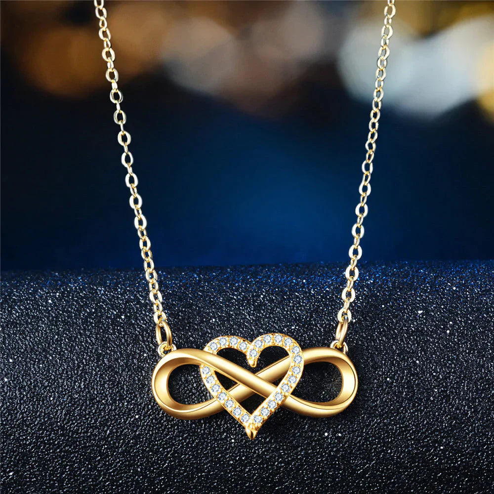 Goldene Halskette mit Herz- und Unendlichkeitsanhänger, verziert mit Kristallen, eleganter Schmuck.