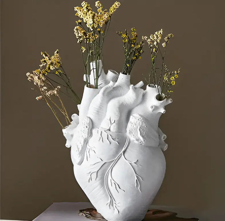 Weiße Herzvase aus Keramik mit getrockneten gelben Blumen, dekorative Wohnaccessoires.