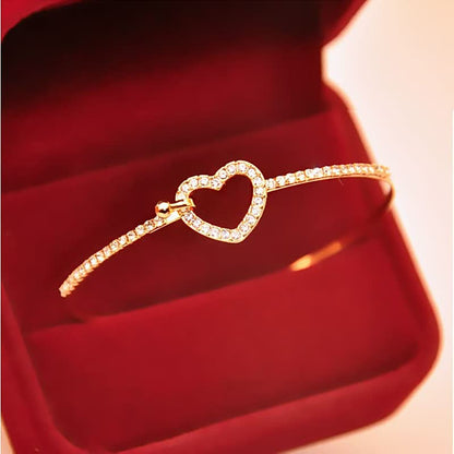 Goldenes Armband mit Herzanhänger, Diamanten, in roter Schmuckschatulle, elegantes Design.