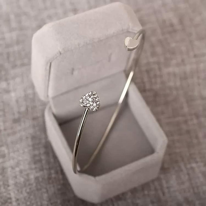 Silbernes Herzarmband mit Diamanten in grauer Schmuckschatulle, elegantes Schmuckdesign.