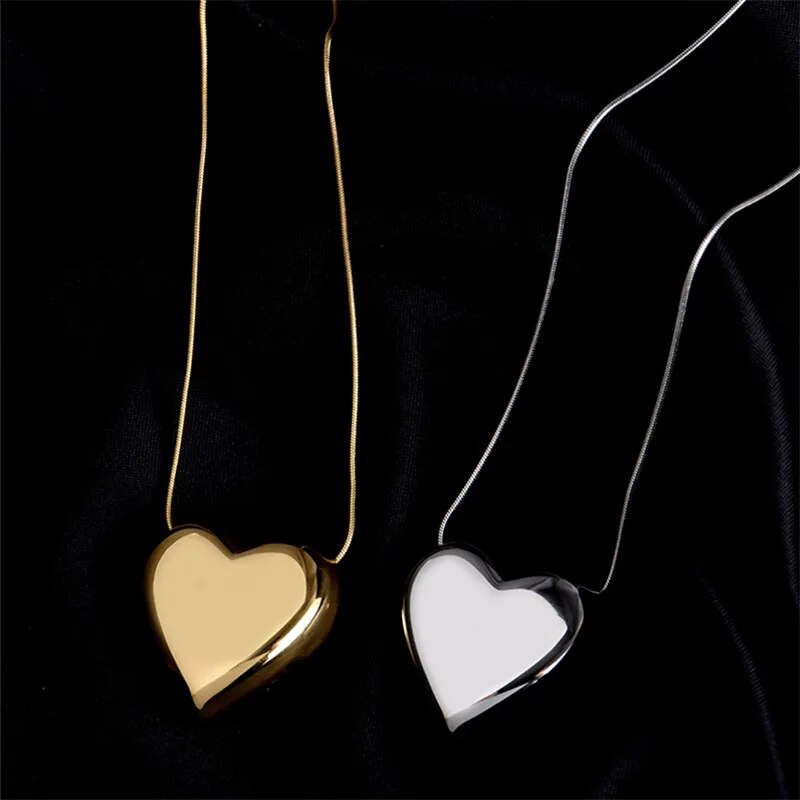 Zwei herzförmige Anhänger, gold und silber, auf schwarzem Hintergrund, Schmuck, Halskette.