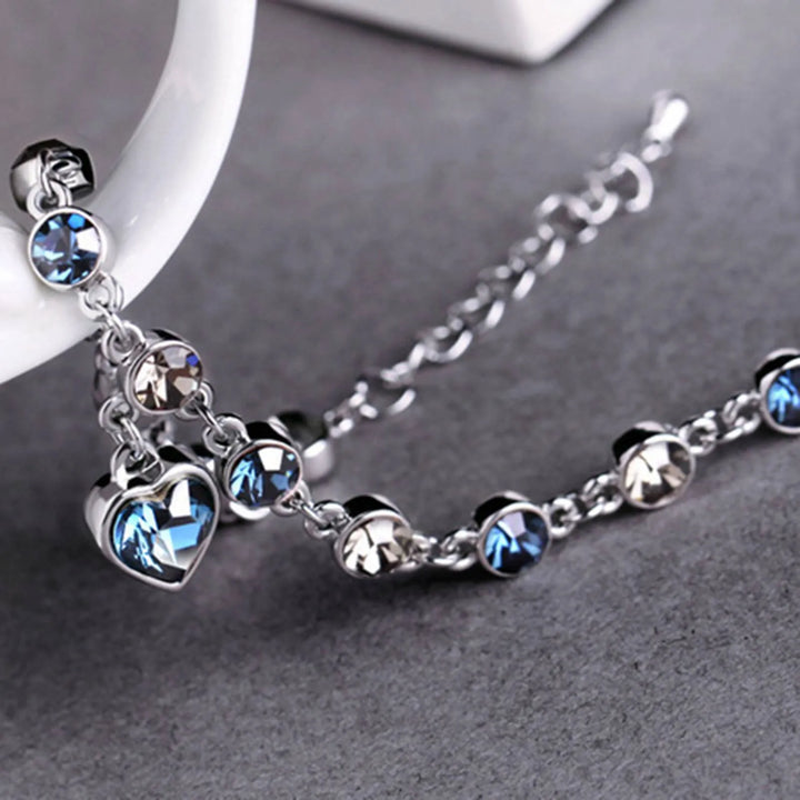 Silberarmband mit blauen und klaren Kristallen, Herzanhänger, eleganter Schmuck für Damen.